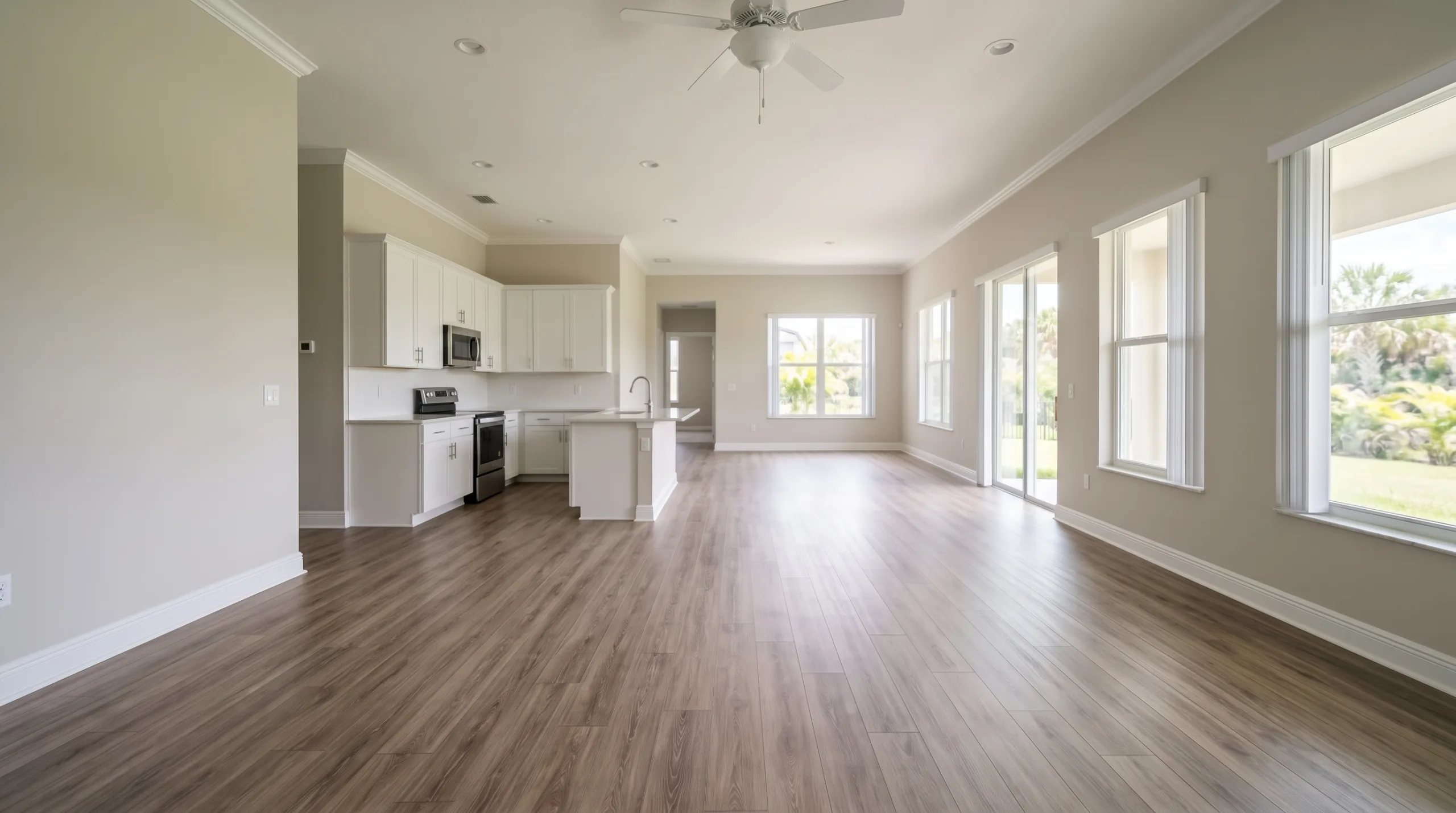 A wide-angle, slightly out-of-focus background view of a freshly deep-cleaned, empty open-concept living and dining area in a middle-class Florida home. Standard white baseboards, smooth light walls, and clean wood-look luxury vinyl plank flooring. Soft natural sunlight filtering through windows. Unfurnished and pristine. Great for a website banner background. No people, no text, no brands.